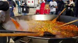 Chefs internacionales deleitan a migrantes con paella