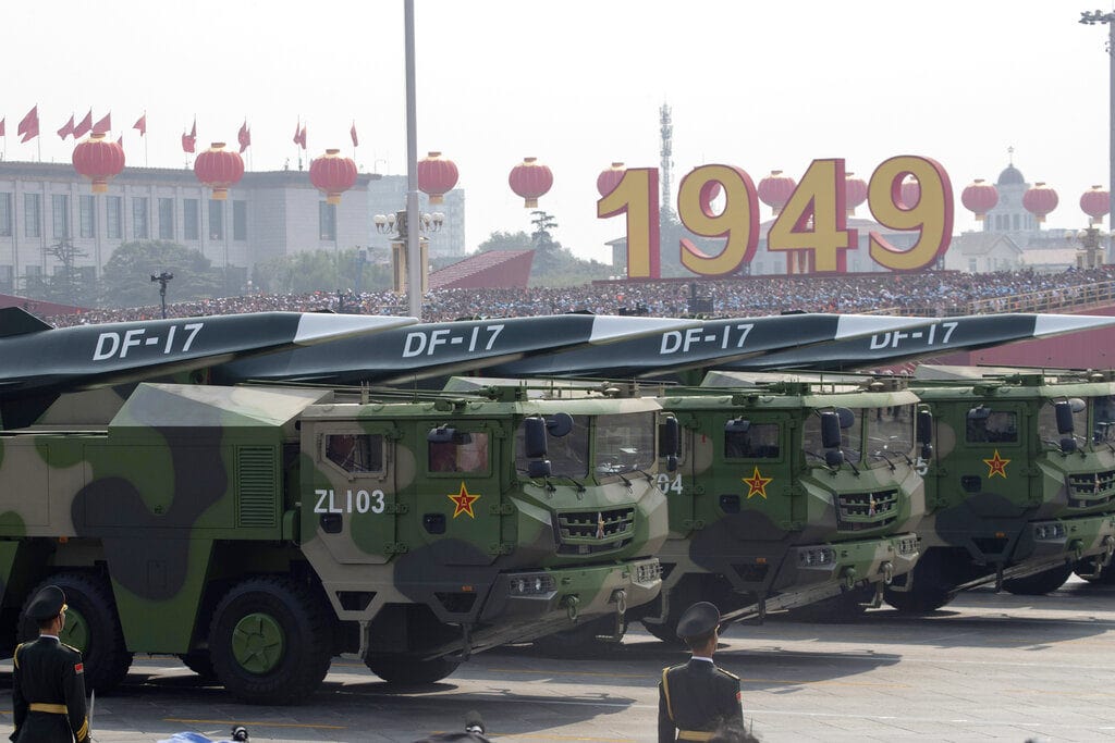 DF-17 ballistic missiles on green camo transporters during a military parade, red lanterns and the large 1949 sign in the background, with soldiers in uniform and the DF-17 markings clearly visible.