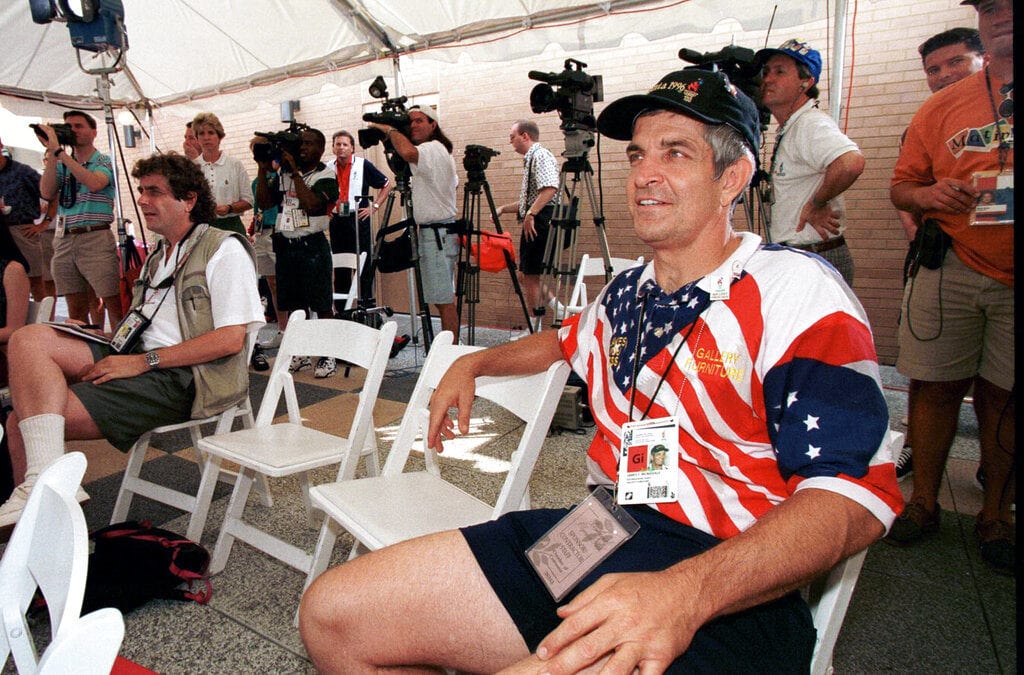Jim McIngvale-inspired Astros superfan wearing a red, white and blue star-spangled shirt, surrounded by reporters and cameras in a press area.