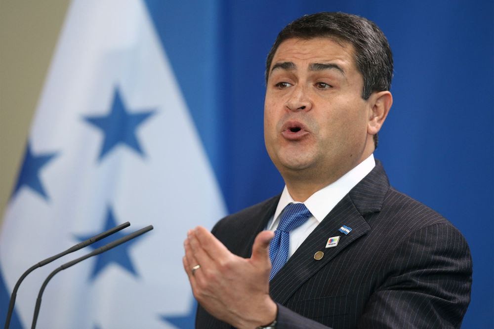 Tony Hernández speaking at a podium with a blue backdrop, a flag in view, and Alexander Ardón and Juan Orlando Hernández referenced in related coverage.