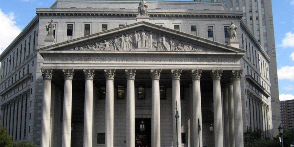 Neoclassical courthouse with tall stone columns and a pediment, referencing Tony Hernández and his brother Juan Orlando Hernández in a high-profile New York case; statuary at roofline adds a civic grandeur.