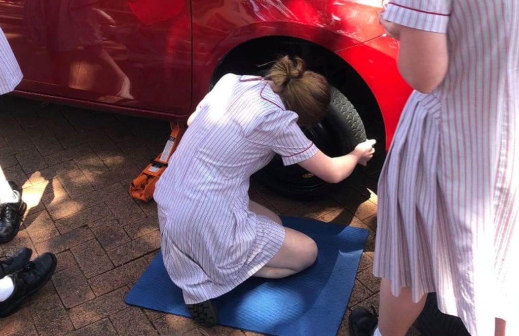 Escuela enseña a niñas a cambiar llantas de un auto para que no dependa de nadie.