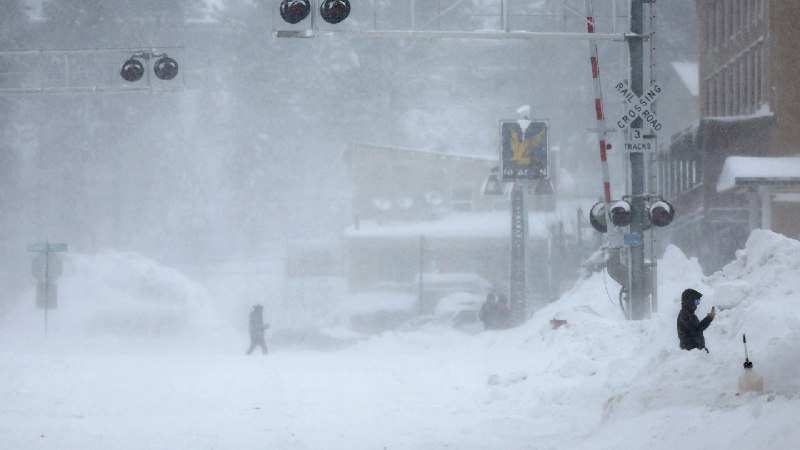 La intensa tormenta invernal en EEUU deja calles cubiertas de nieve y hielo, con semáforos y peatones avanzando en medio de la tormenta.
