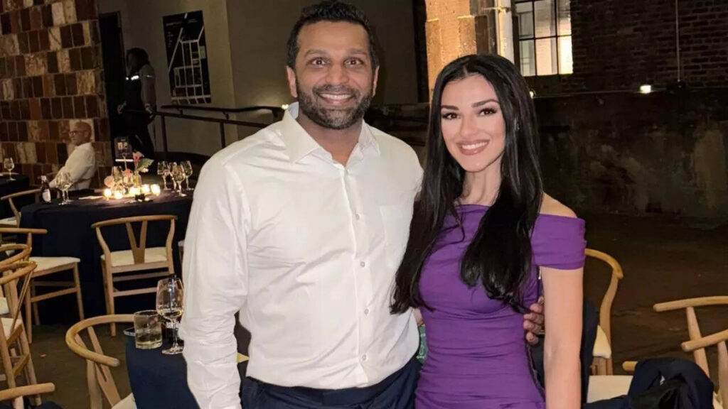 Kash Patel and Alexis Wilkins together at a night event; Kash in a white shirt and Alexis in a purple dress, both smiling at the camera
