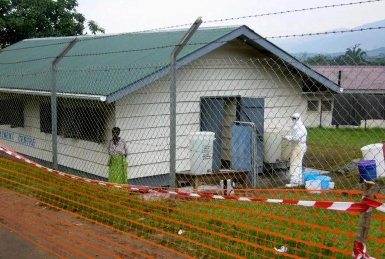 Valla metálica y contención sanitaria con personal de protección en un campamento por el nuevo brote de Ébola durante la epidemia, en alerta mundial.