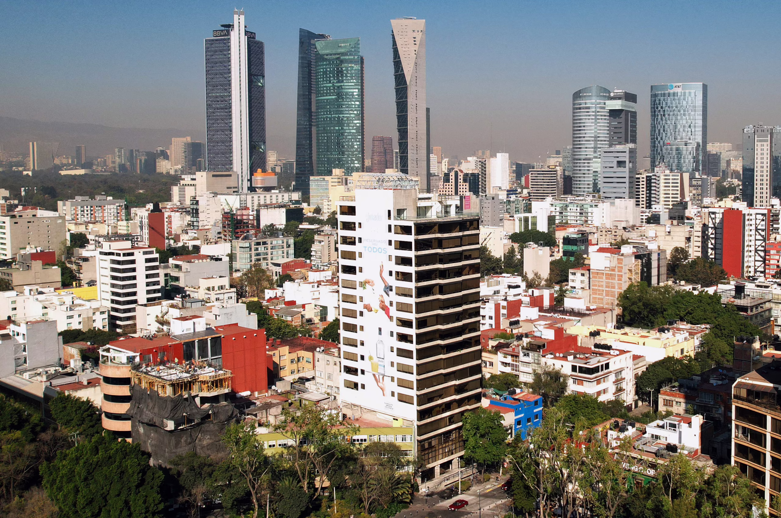 Panorámica de rascacielos y edificios altos en Ciudad de México, con cielo azul y conjuntos urbanos de tonos grises y blancos al frente.