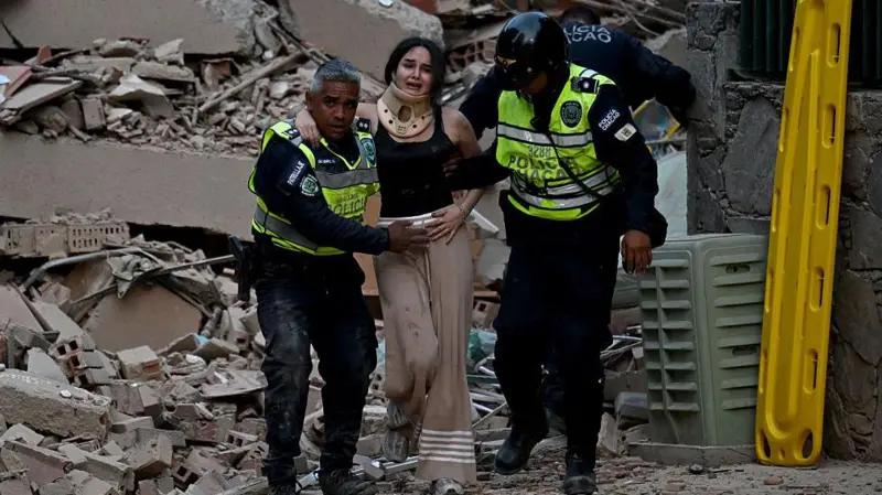 Policías ayudan a una mujer entre escombros en Venezuela después de los terremotos y las más de 130 réplicas que dejaron daños graves.